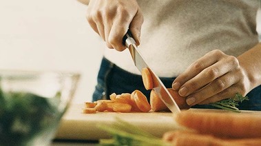 A woman chops carrots, emphasizing healthy eating habits.