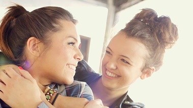 Two teenage girls hug each other expressing warmth and friendship