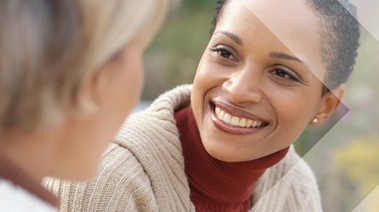 Two women chat in a serene, green field.