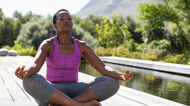 Woman meditating near water