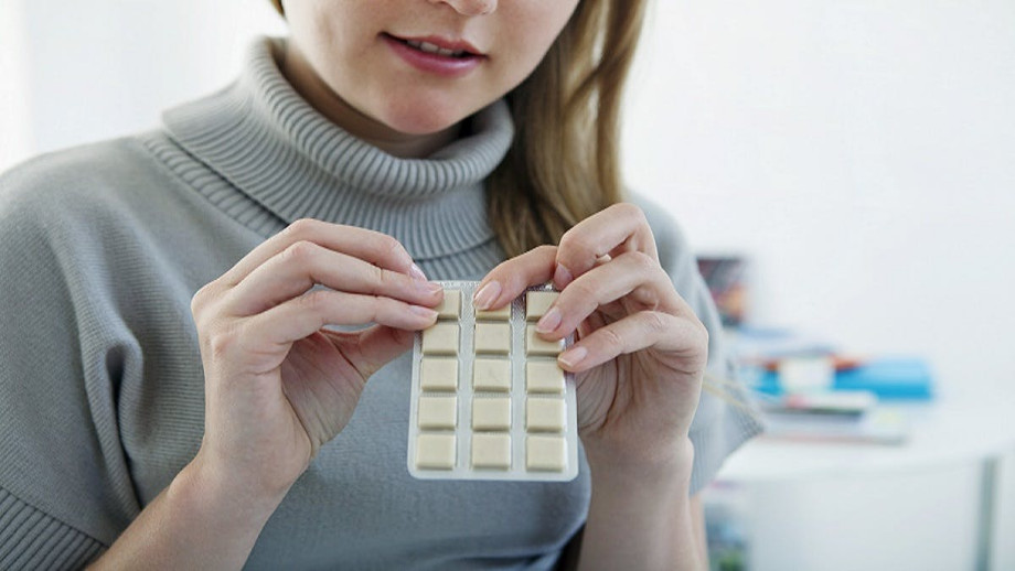 Young woman holding a pack of nicotine gum.