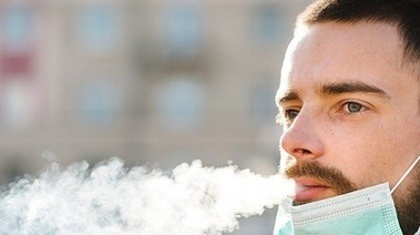 man with mask blowing smoke