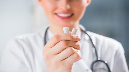 Doctor holding up two pieces of white gum.