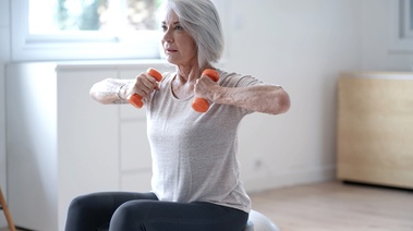 An older woman performs exercises on a fitness ball, showcasing her commitment to fitness and well-being
