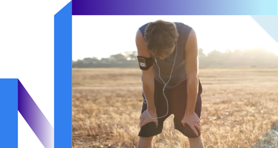 A man in a field leans forward, listening intently through his headphones.