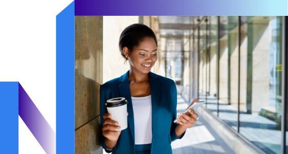A woman in a blue blazer smiles while looking at her smartphone.