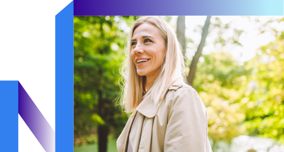 A smiling woman in a park, surrounded by greenery
