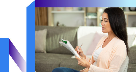 Woman sitting on a couch focuses on solving a crossword puzzle