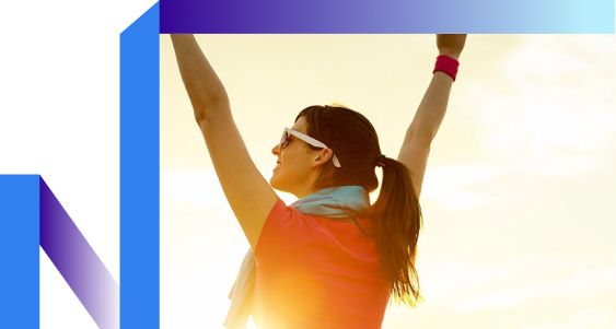 A woman joyfully raises her arms in a vibrant outdoor setting.