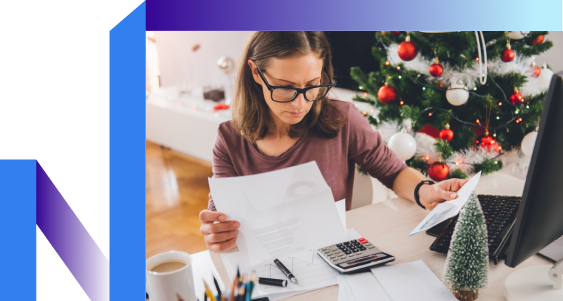 A woman in glasses sits at a desk, focused on a calculator and papers.