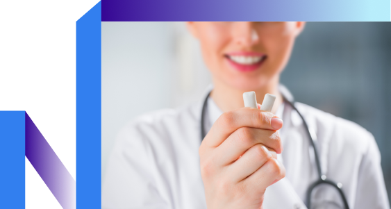 A smiling healthcare professional, wearing a white coat and stethoscope, holds two lozenges.