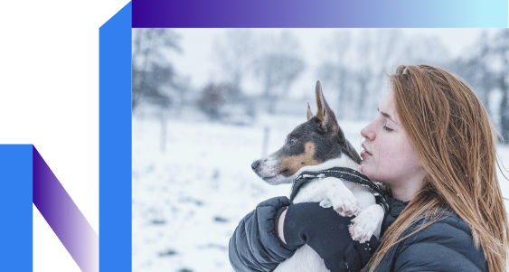 A woman cradles her dog in the snow, embodying a serene moment of joy and calmness during her journey to quit smoking.