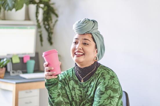 A woman in a turban holds a pink cup, symbolizing relaxation in her smoke-free journey.