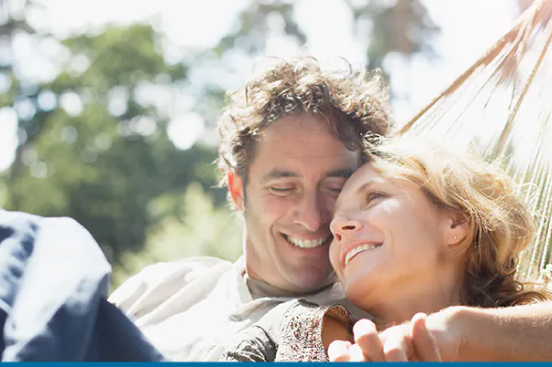 Couple holding hands and smiling in hammock