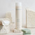 Invigorating Cleansing Lotion Face and Eyes, 250 ml bottle sitting on a table next to sandstone and bars of soap.