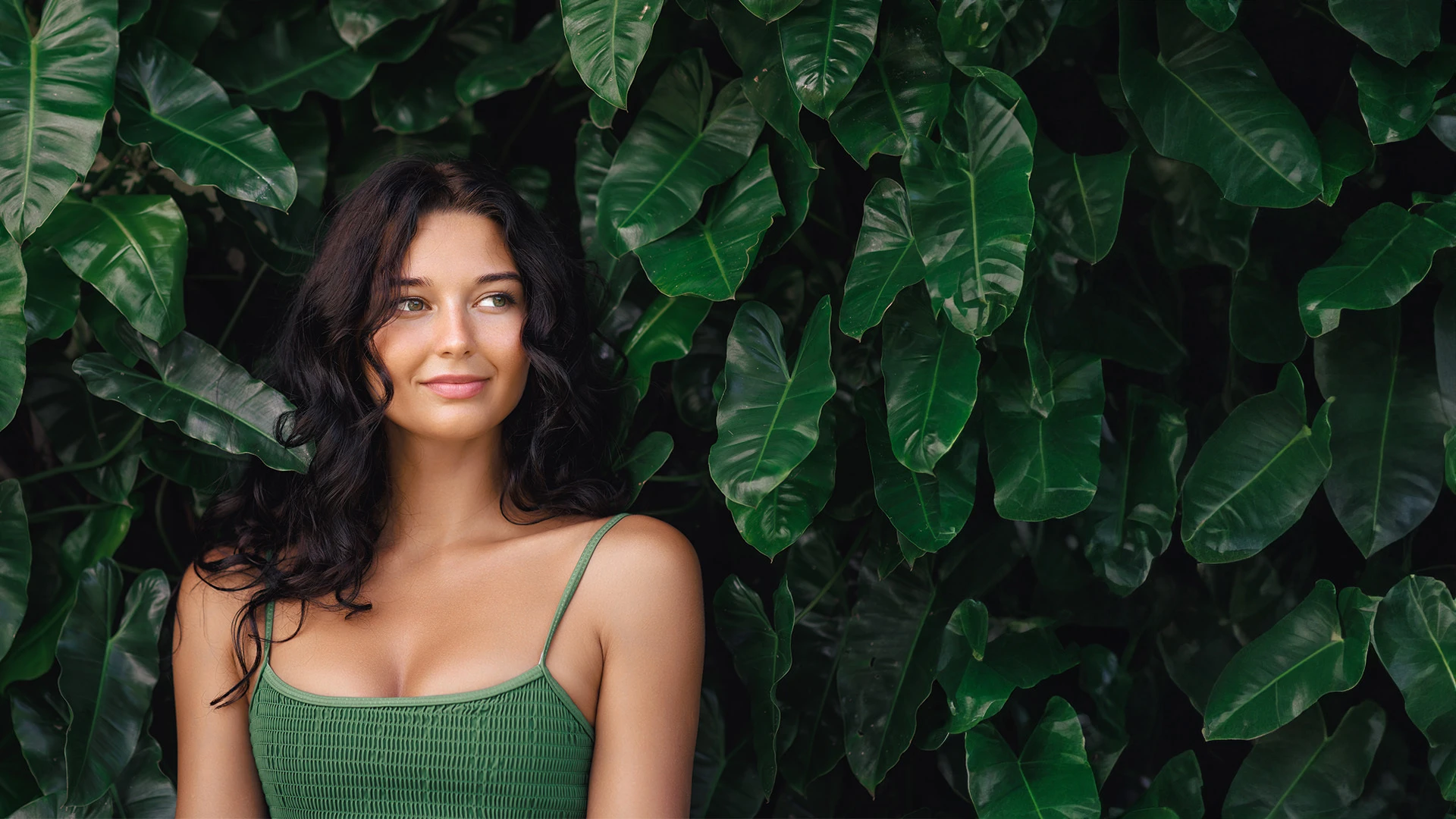 Woman surrounded by tropical foliage.