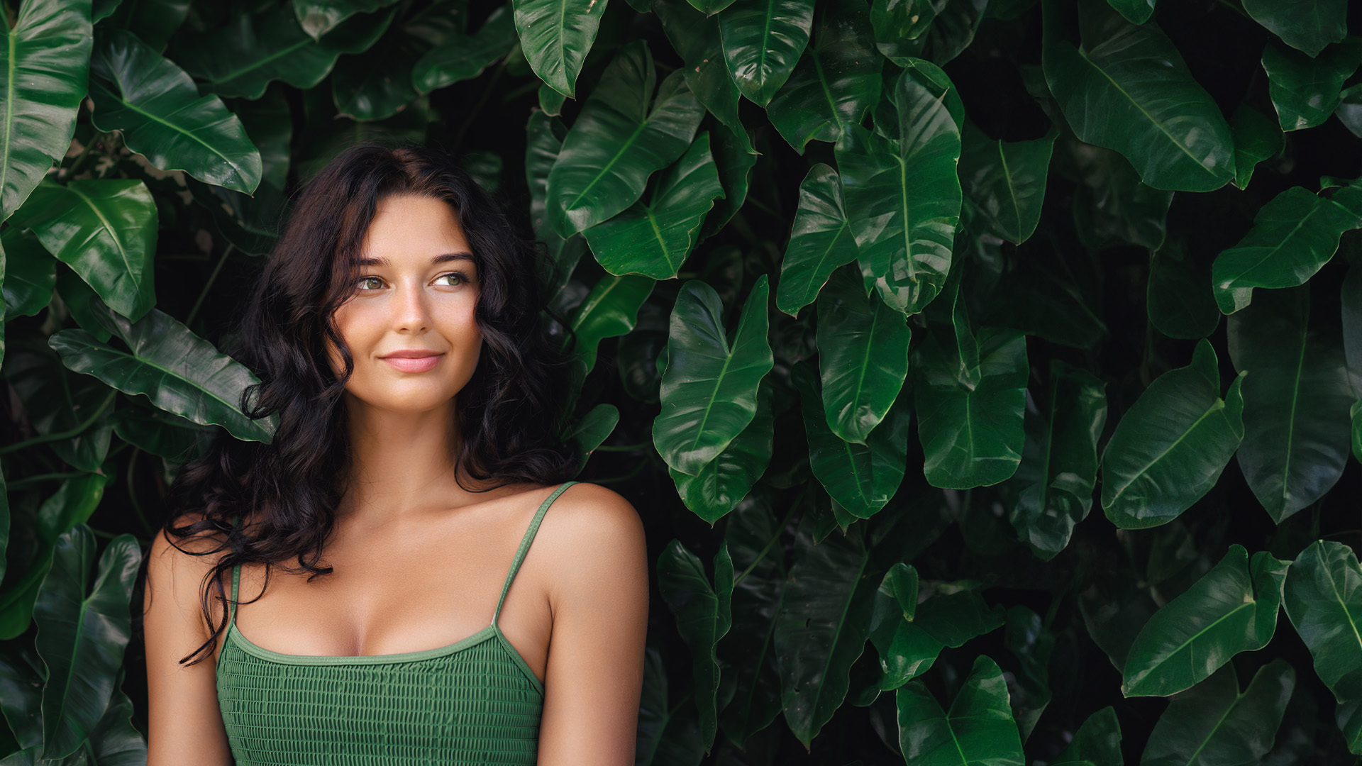 Woman standing in tropical foliage.