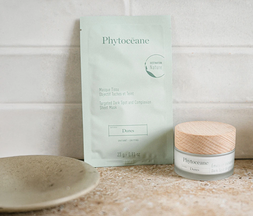 Phytoceane Dark Spot Brightening Cream next to Destination Dunes Targeted Dark Spot and complexion sheet mask, on a countertop.