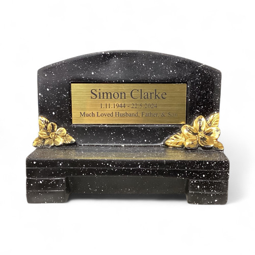 A small black rectangular bench memorial keepsake. Made from black resin with decorated gold flowers. Personalised gold coloured plate showing personalised message. A small black rectangular bench memorial keepsake. Made from black resin with decorated gold flowers. Personalised gold coloured plate showing personalised message.