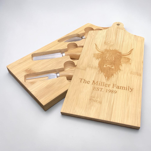 Personalised bamboo cheese board with highland cow design. Engraved with a customised message on top of sliding lid which reveals 3 cheese knives