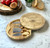 A round wooden cheese board with a swivel lid engraved with the text GRANDAD'S CHEESE BOARD and a graphic of cheese. The board opens to reveal a set of four stainless steel cheese servers with wooden handles.