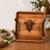 A square wooden serving tray featuring a dark brown laser-engraved illustration of a Highland cow head in the centre. The tray has a natural wood grain finish and is equipped with two dark brown leather handles attached to the sides.