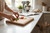 Hand chopping vegetables on large personalised wooden butcher block board in modern kitchen, centered engraving visible