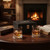 Personalised black wooden whisky presentation gift set with customised message. Presentation box is situated opposite an open fireplace in cosy room setting with half filled whisky glasses.