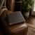 Lifestyle image of brown oiled filled wallet with white stitching , engraved with the initials "ATLD". Resting on the side of a brown leather sofa arm with living room background.