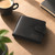 Personalised black leather wallet with initials engraved on the front.  Wallet is laying on a wooden desk with green plant and cup of coffee displayed to its left.