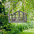 Personalised sunset bird feeder seat with custom engraved wooden plaque and swing-style design hanging from a tree in a garden setting.