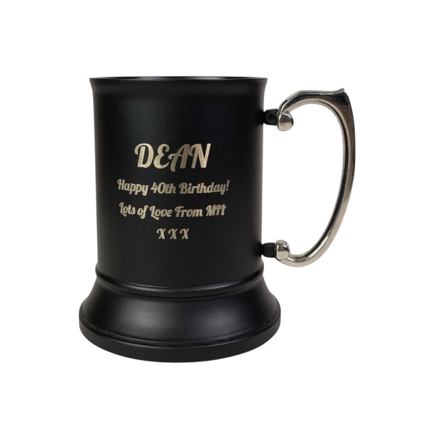 A matte black beer tankard with a silver-coloured handle. The tankard is engraved with the text: DEAN, Happy 40th Birthday!, Lots of Love From MIL, X X X. The tankard features a wide base and a smooth, cylindrical body with a metallic finish.
