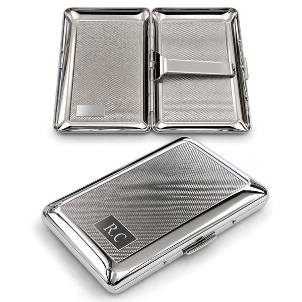A rectangular silver-toned metal cigarette case with a textured crosshatch finish. The closed case features a black rectangular inlay with the engraved letters R.C. The open case reveals a polished interior with a metal spring bar.