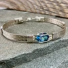 This CUSTOM bracelet features a Rainbow Topaz. You have your choice of metals, bracelet band style and size to complete this wire wrap beauty. Shown in an all Argentium Silver band with a New Classic style, it'a a sure winner for anyones jewelry wardrobe. Make you selection today, and HAVE IT YOUR WAY.