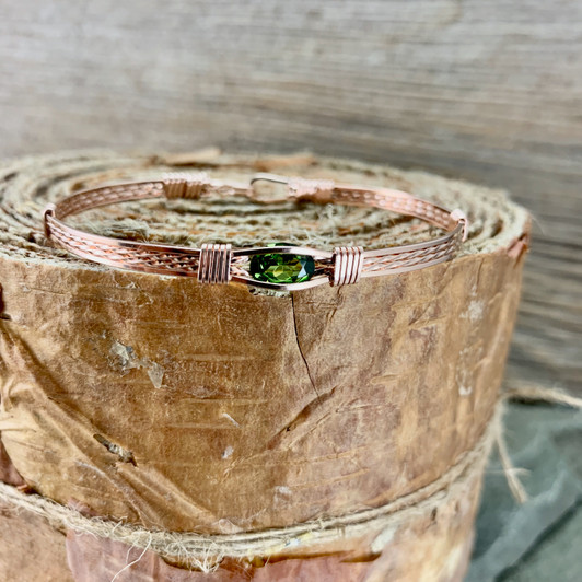 Peridot is the birthstone for August and known for its unique green color. This synthetic Peridot is shown in an all rose gold bracelet band but available in additional choices of metal. We also offer two metal band designs from the Classic which is shown in the photo as well as a Minimalist which has no twisting in the metal band. 