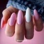 Elegant manicure featuring long, glossy almond-shaped nails in a delicate pastel pink shade, complemented by a contrasting solid white accent nail. The image showcases a soft pink and white nail colour combination associated with Makear 596 Hybrid Gel Polish, styled against a denim background.