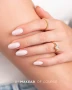 Elegant manicure featuring glossy, softly rounded almond-shaped nails in a delicate milky white shade with subtle pink undertones. The natural-looking nail design showcases the smooth, creamy finish associated with Makear 602 Milky French Hybrid Gel Polish, complemented by elegant gold rings.