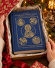Ignatius Catholic Study Bible: Old and New Testaments: Leather revealed inside a Christmas gift box surrounded by festive wrapping, evergreen branches, warm lights, and Nativity décor.
