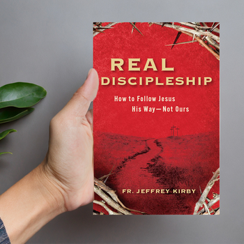Hand holding Real Discipleship, angled to clearly display the cover.
