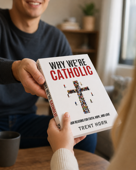 One person hands a copy of Why We’re Catholic to a friend in a warm indoor setting, with the front cover clearly visible during the exchange.