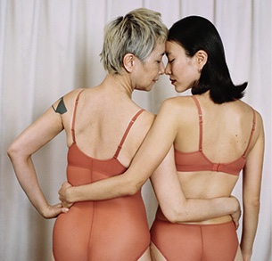 The backside of two women with arms around each other, facing each other