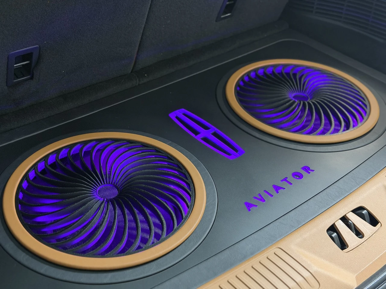 Backlit Lincoln emblem and Aviator script glowing purple through turbine subwoofer grilles