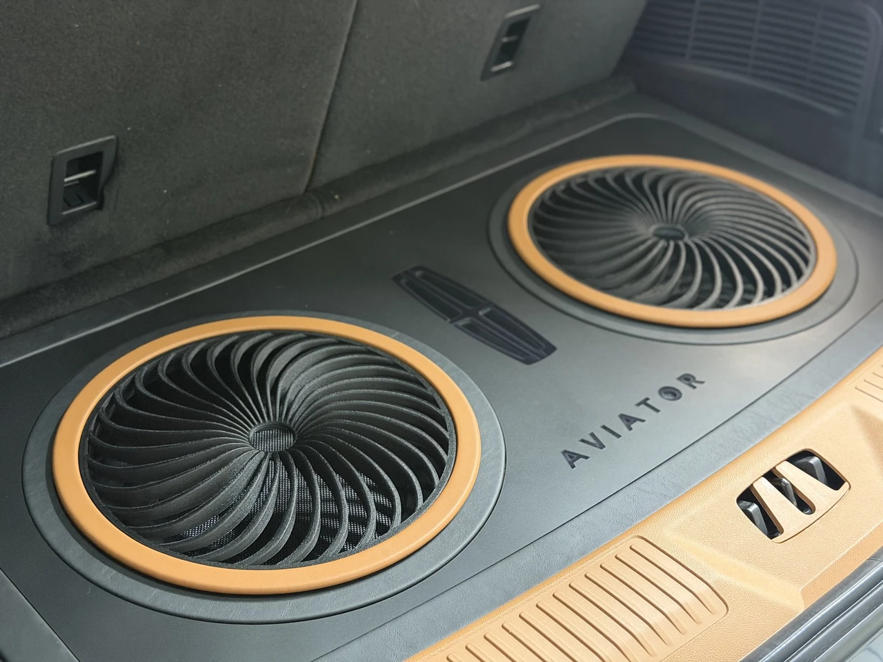 Custom dual subwoofer enclosure with turbine-style grilles built into the cargo floor of a 2026 Lincoln Aviator