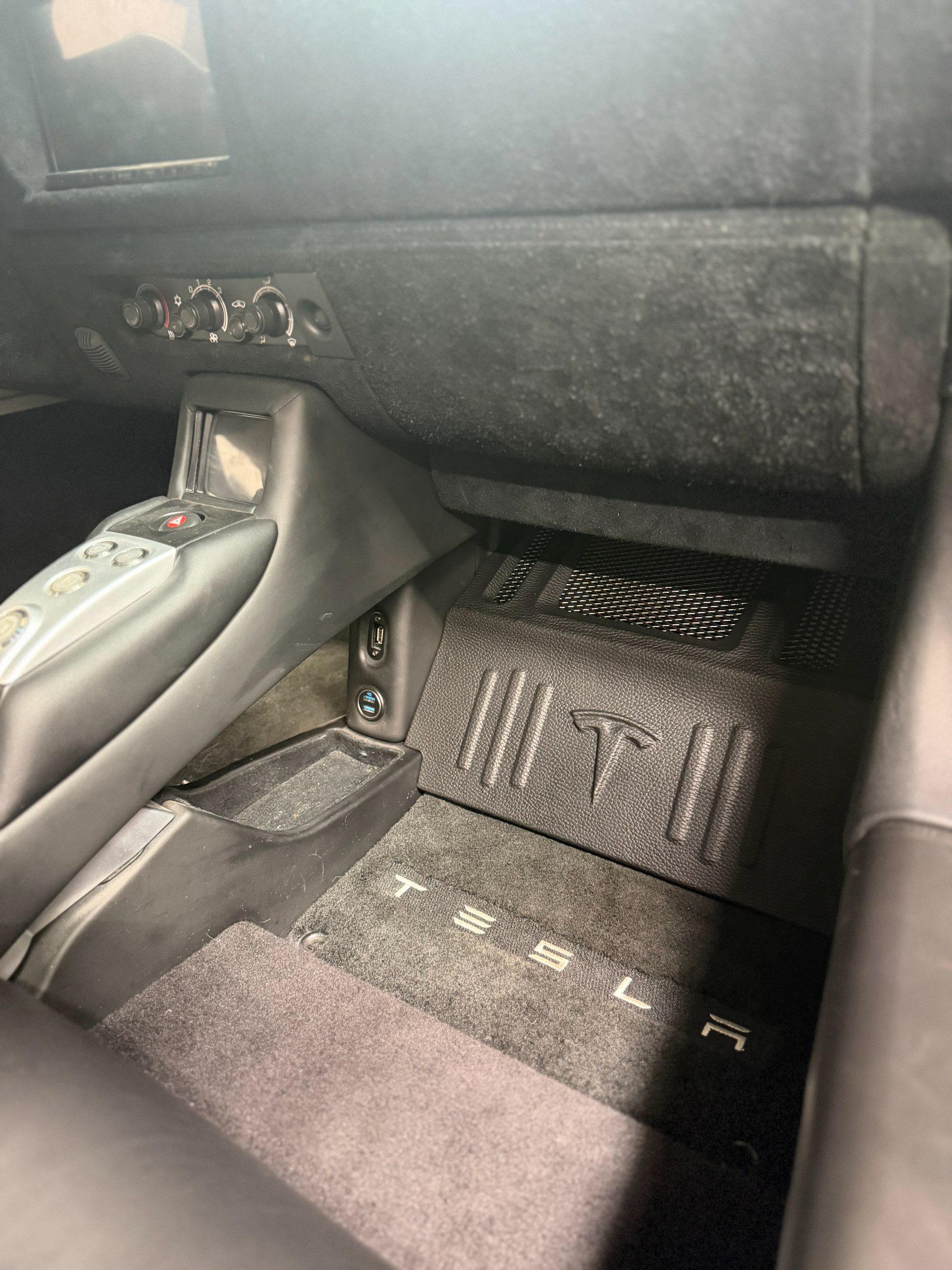 Custom kick-panel subwoofer enclosure finished in factory materials in the Tesla Roadster