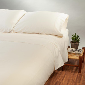 Natural solid color organic cotton Jersey Sheet Set shown on a bed.