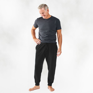 Person wearing Black solid color organic cotton Unisex Fleece Jogger pants shown from the front. Person wearing Black solid color organic cotton Unisex Fleece Jogger pants shown from the front.
