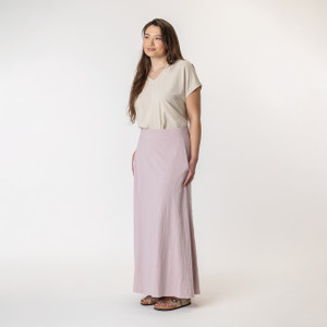 Full body side view of model wearing organic cotton maxi skirt in lavender. Full body side view of model wearing organic cotton maxi skirt in lavender.