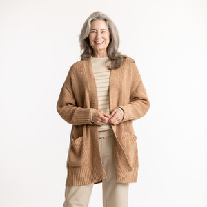 Front view of model with hands in pocket wearing organic cotton cardigan sweater in color turmeric Front view of model with hands in pocket wearing organic cotton cardigan sweater in color turmeric