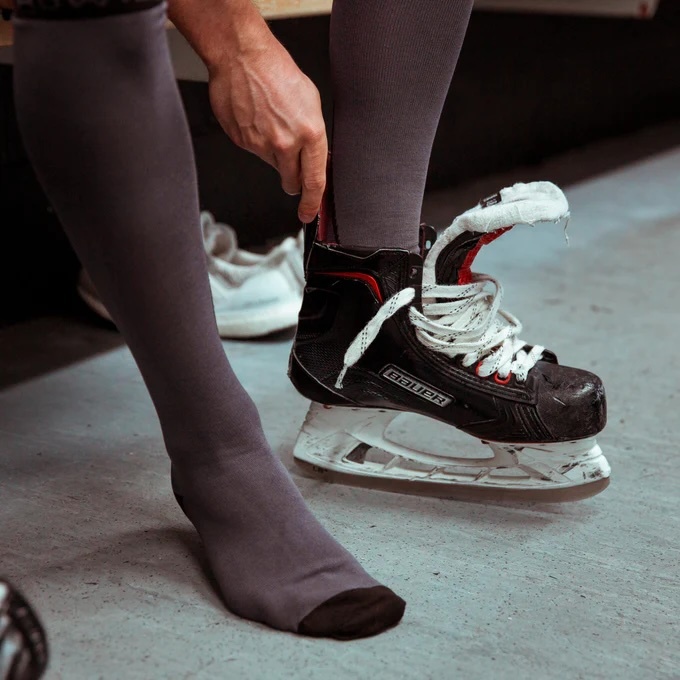 Hockey socks and player putting on skate