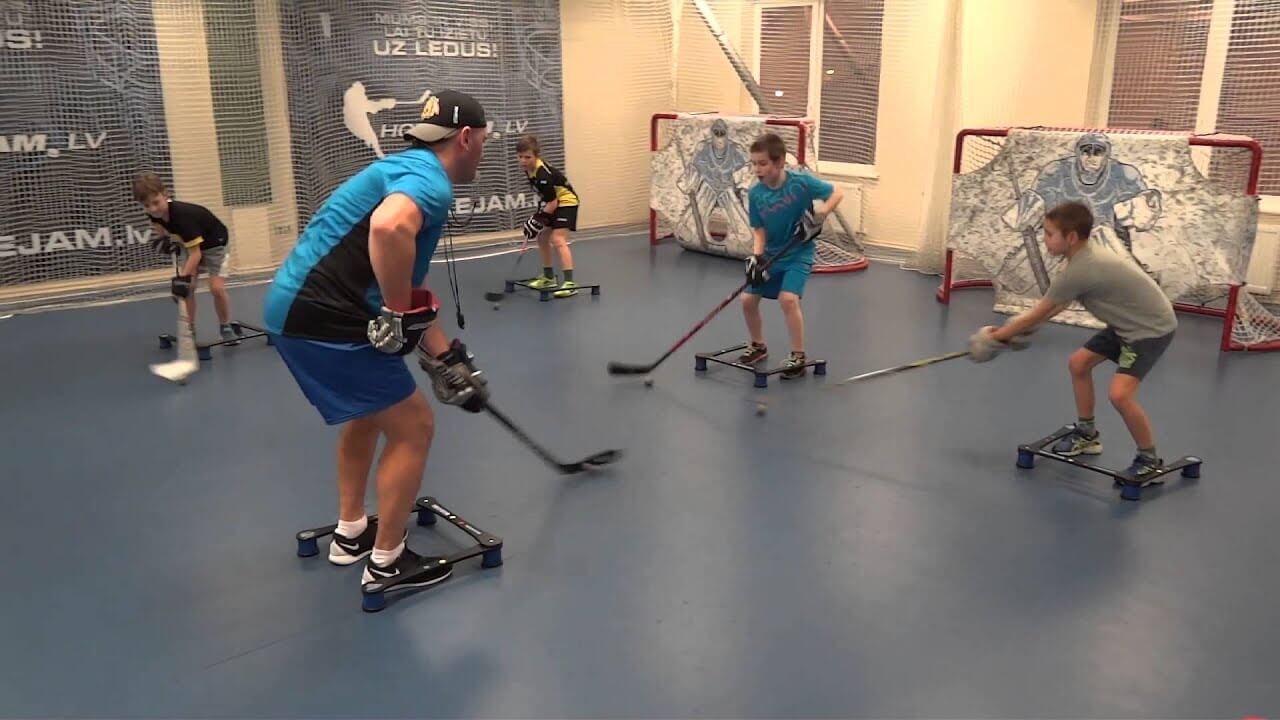 Kids practicing with a coach indoors off ice